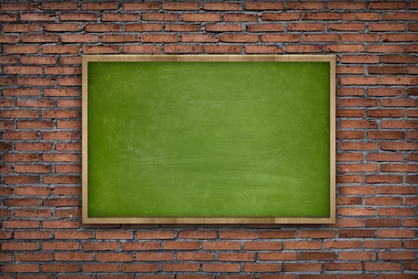 Green blank blackboard with wooden frame on brick wall background