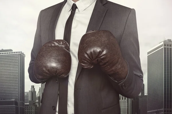 Businessman in boxing gloves on cityscape background