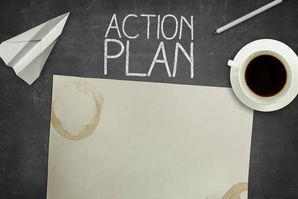 Action plan concept on black blackboard with empty paper sheet