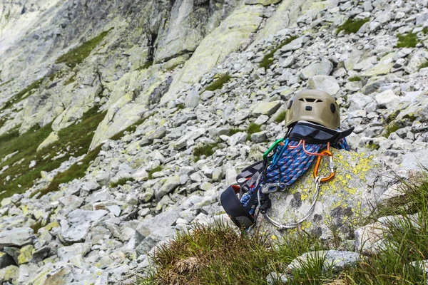 Rope, helmet, carabiners, climbing harness and descender on the rock