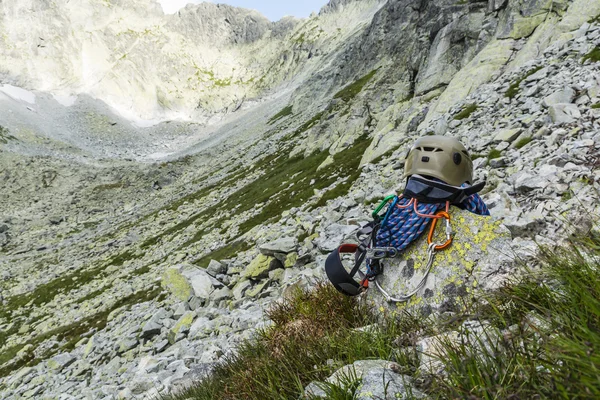 Rope, helmet, carabiners, climbing harness and descender on a rock in the valley