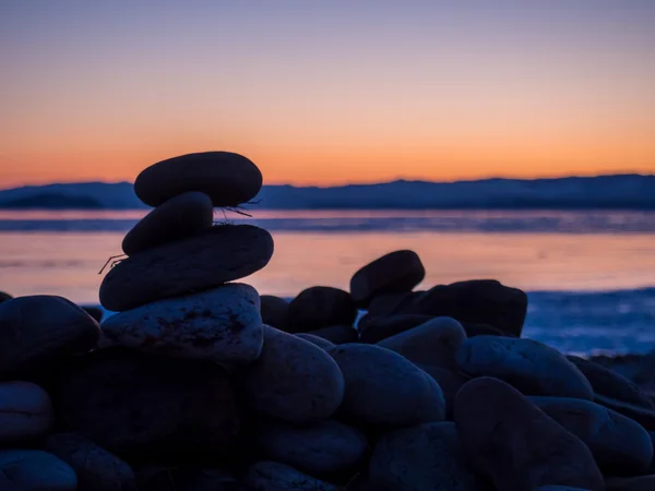 Round stones piled pyramid on a background of sunrise on winter