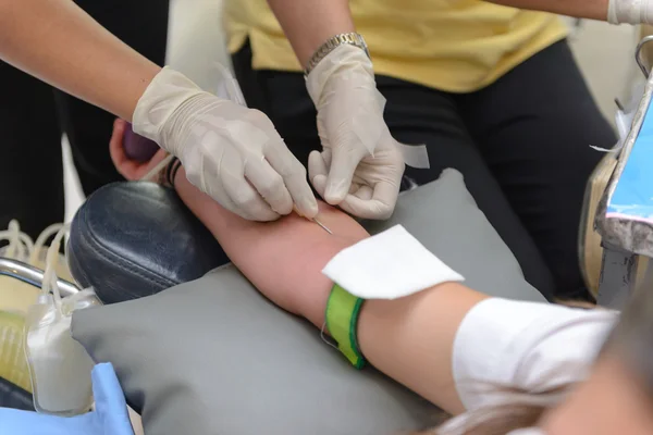 Nurse giving an intravenous injection to blood donor at blood donation