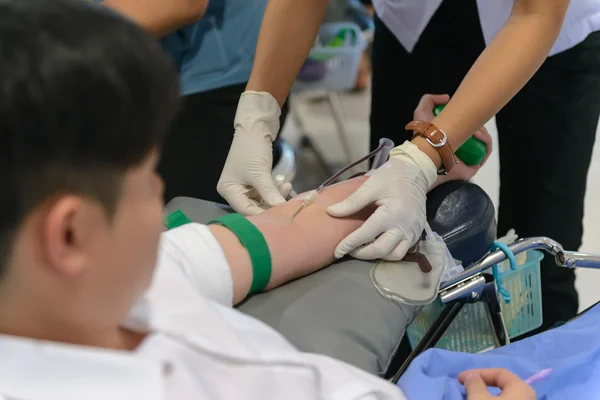 Nurse giving an intravenous injection to blood donor at blood do