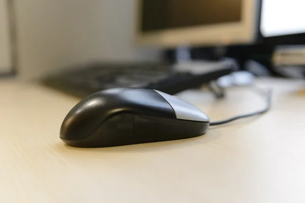 Closeup computer mouse before computer desktop on brown wooden d