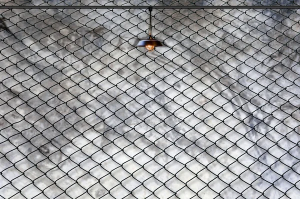 Lamp with wired fence and Grungy concrete wall