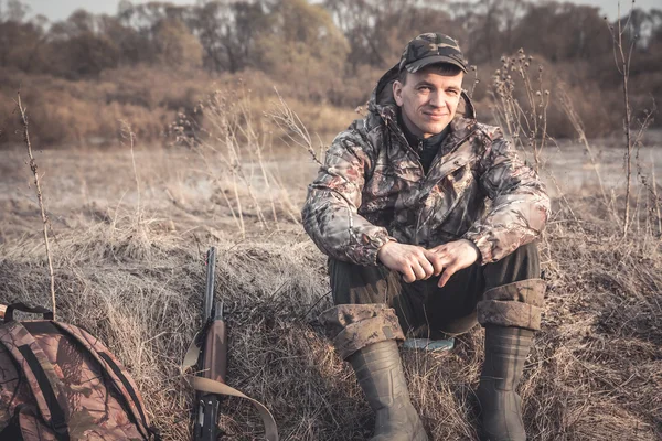 Hunter man in rural field with shotgun during hunting season