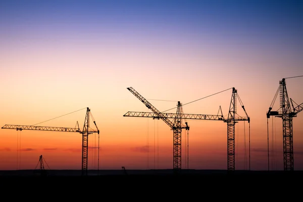 Construction site with cranes against a sunset sky