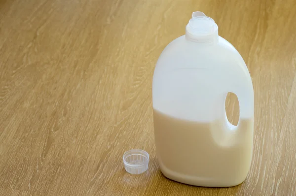 Liquid detergents bottle with it\'s cup next to it