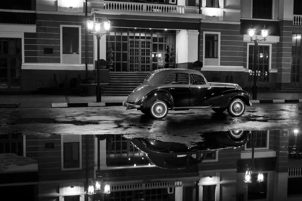 Old retro car stay on asphalt city road at rainy night