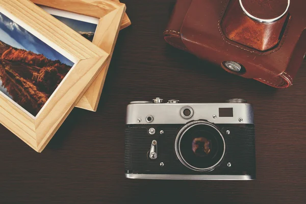 Retro vintage camera and photos in frame on wood background