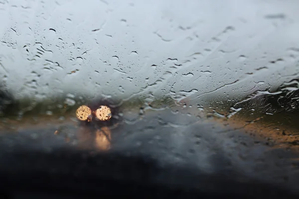 Drive car at heavy rain. Water drops at window