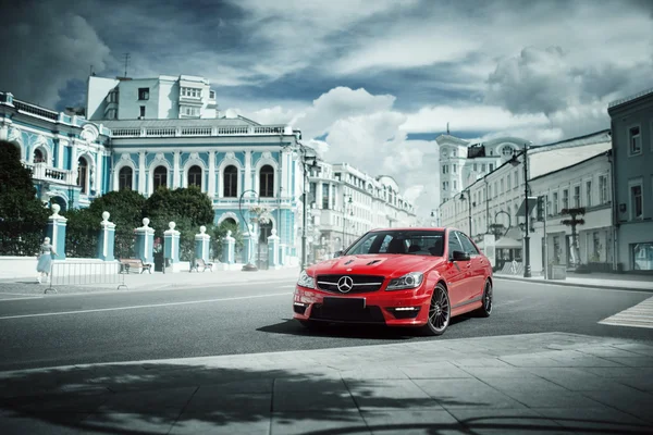 Red car Mercedes-Benz C63 AMG stay on asphalt road in the city Moscow at daytime