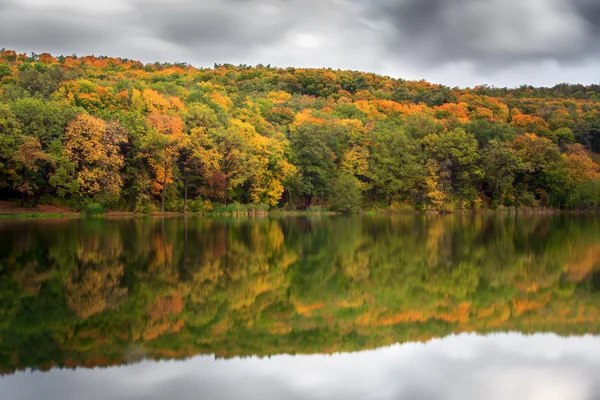Beautiful autumn landscape. Green golden forest reflect on water lake