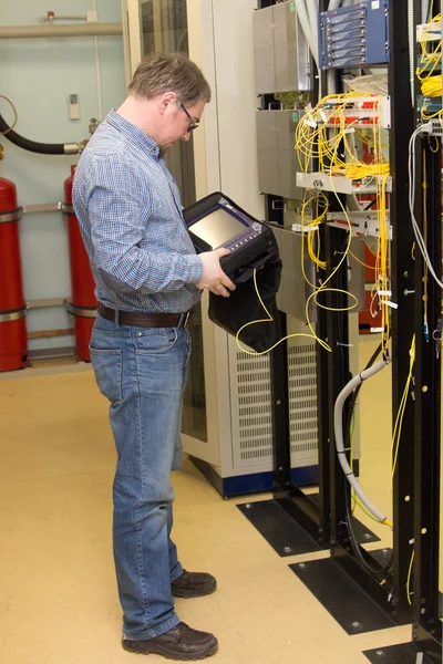 Engineer with optical tester in data center