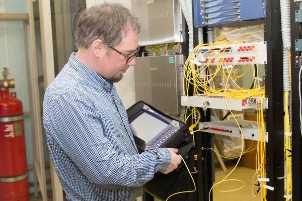 Engineer with optical tester in data center