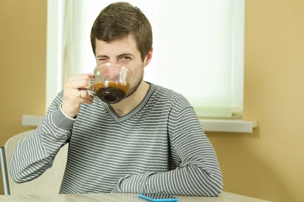 Man drinks coffee in the kitchen.