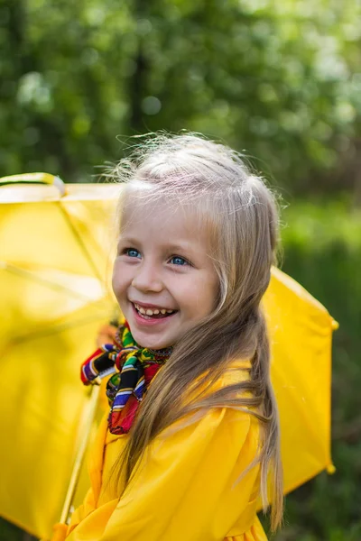 Portrait of joyful girl in a yellow dress with a yellow umbrella