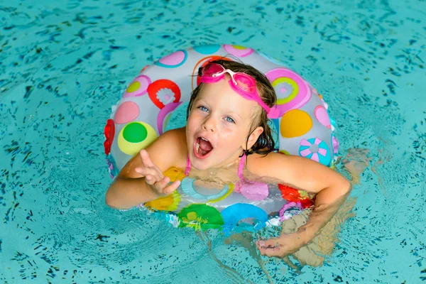 Funny little girl in pink goggles in the swimming pool