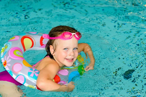 Funny little girl in pink goggles in the swimming pool