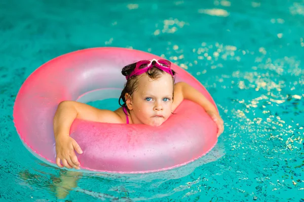 Funny little girl in pink goggles in the swimming pool