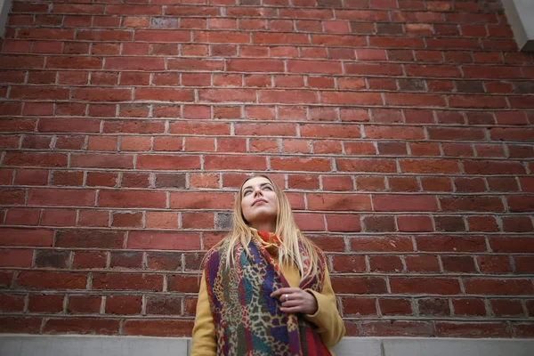 Portrait of young happy woman by the brick wall