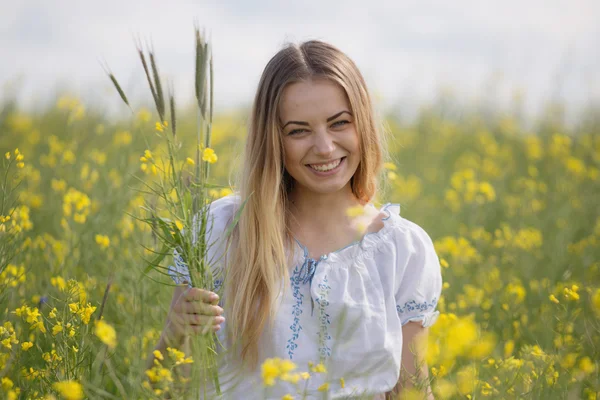 Girl with a wreath of colorful flowers on her head, in a flowering yellow field