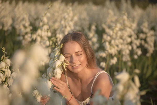 Princess. Young beautiful pretty woman posing in long evening luxury dress against bushes with white flowers