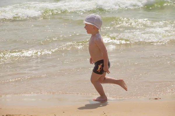 Happy baby running from surf on the beach