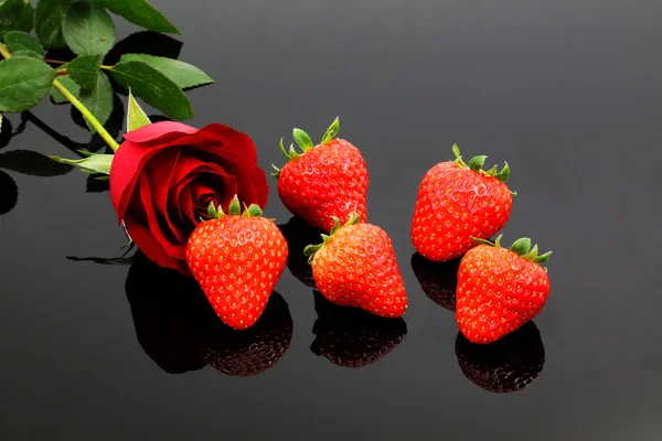 A Red Rose and Strawberries on a Black Background