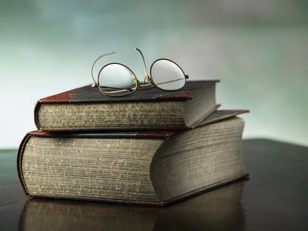 Old books with antique reading glasses on colorful background
