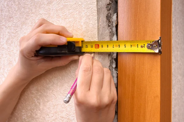 Hands measuring wall with tape measure, closeup