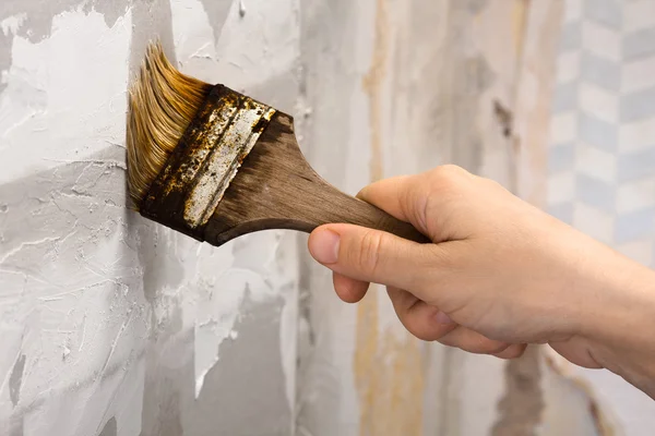 Hand smearing wall with glue with brush