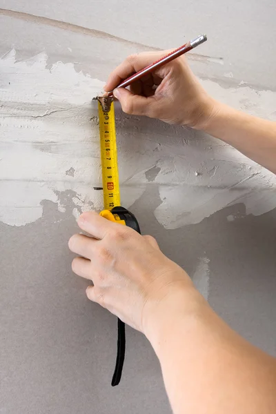 Hands measuring wall with tape measure, closeup