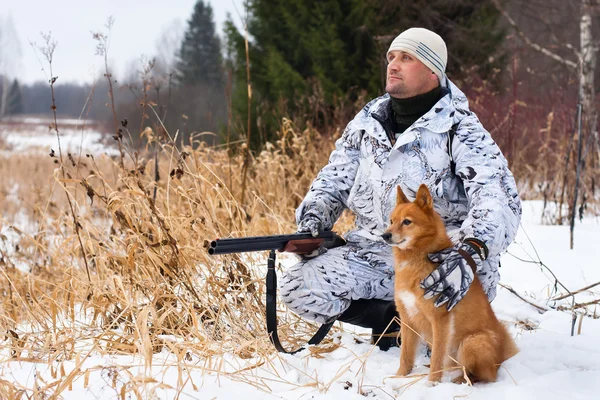 Hunter with gun and dog in winter