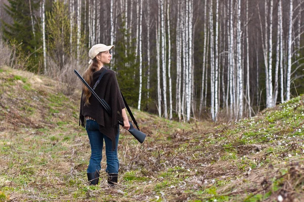 Woman hunter with gun in forest