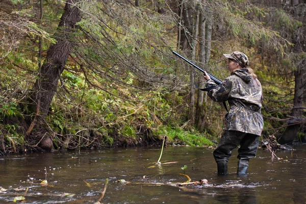 Woman hunter shooting on the river