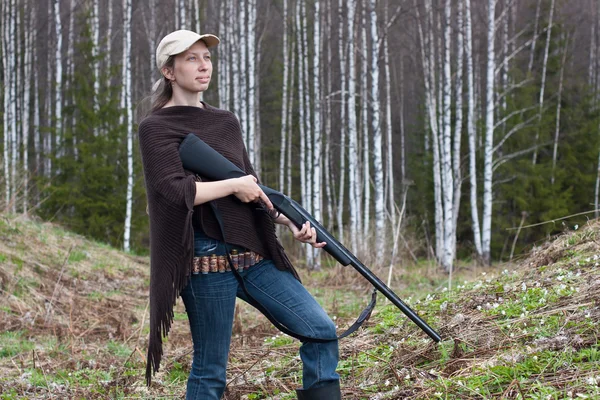 Woman hunter with shotgun in spring forest