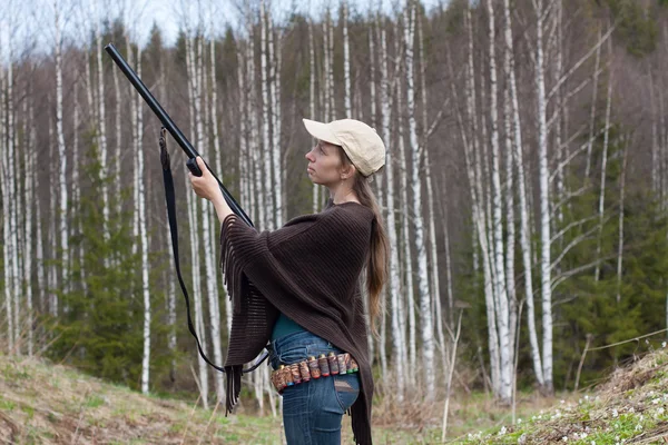Woman hunter  takes aim from a gun in the forest