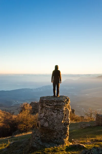 Man on the cliff in mountains at sunset