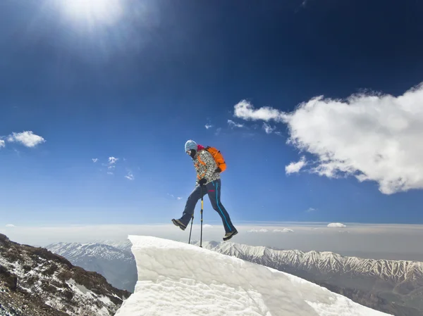 Man jumping on a snow cornice in mountain sunrise