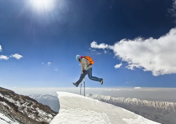 Man jumping on a snow cornice in mountain sunrise