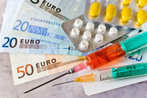 Different pills and syringe with Euro money - healthcare cost