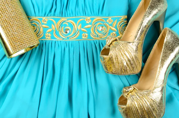 Gold high-heeled shoes, clutch bag and blue dress with gold acce