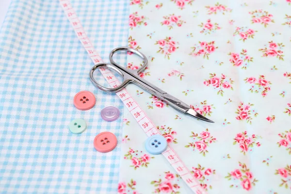 Sewing tools in a vintage fabric background with scissors and buttons