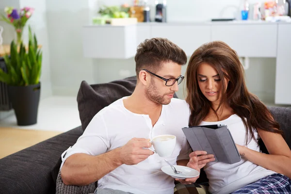 Woman with tablet and husband reading newspaper