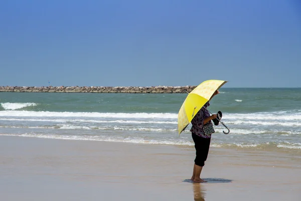 Woman with big umbrella waiting for someone on the the beach