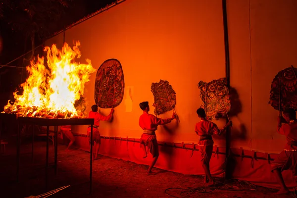 Rachaburi, Thailand - April 14, 2015: Youth show perform Grand Shadow Play in night at Wat Khanon.Rachaburi, Thailand.The ancient performing art involves manipulating puppets of cowhide with coconut shell fire. in front of a backlit white screen.