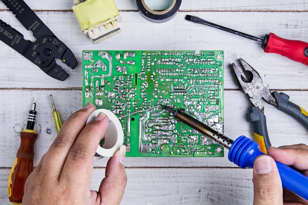 Serviceman soldering circuit board with soldering iron in the se