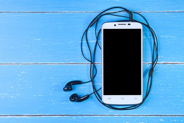 Smart phone and earphone on the blue wooden background